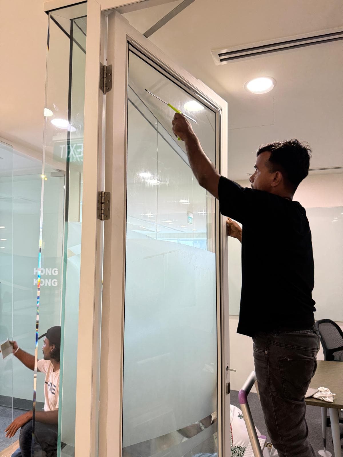 Technician replacing shattered window glass in a Singapore HDB living room